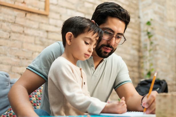 Image of a father and young son writing together as a poignant representation of the crucial role relationships play in supporting individuals during and after incarceration.