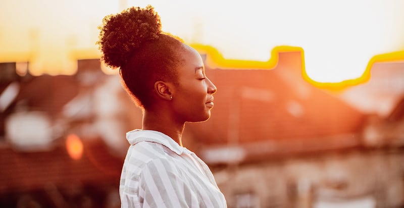 A happy and contemplative African American woman, setting the tone for the blog on mastering the art of self-care after a period of incarceration.
