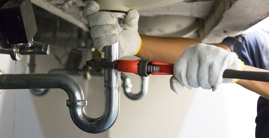 Student in plumbing apprenticeship program repairs a clogged sink during basic plumbing training.