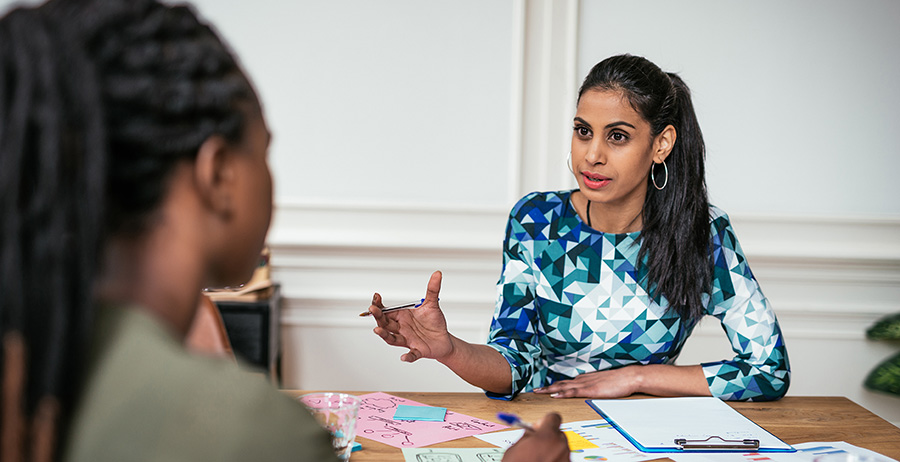 Reentry counselor supports a woman taking notes during a transitional housing intake meeting.