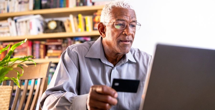 Man in his late 50s sits at a table, focused on making a budget on his laptop.